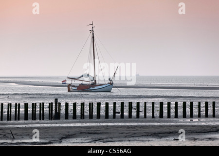 Die Niederlande, Nes, Ameland Insel, gehört zum Wadden Sea Islands. Segelboot auf flachen Schlamm im Hafen. Stockfoto