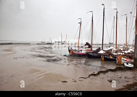 Die Niederlande, Nes, Ameland Insel, gehört zum Wadden Sea Islands. Segelboote auf Schlamm Wohnung im Hafen. Stockfoto