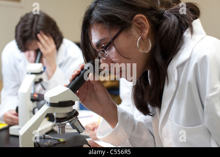 SchülerInnen mit weißen Laborkitteln verwenden Mikroskope in Süd-Texas High School Wissenschaft Klassenzimmer Stockfoto