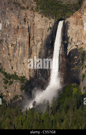 Yosemite National Park uns Wasserfälle Bridal Veil Falls seidig Frühling voller Durchsatz, Nebel, die an der Basis über Bäumen, bezeichnendes Licht auf Felswand niedrigen Winkel Stockfoto