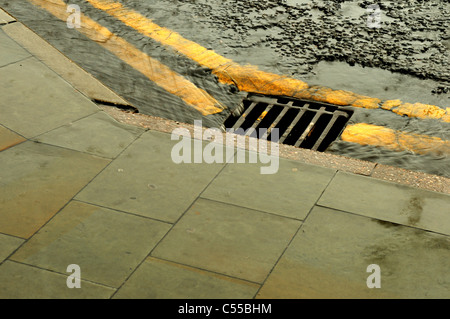 Regenwasser läuft Bach runter auf die Straße. Stockfoto