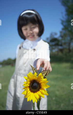 Ein Mädchen mit einer Blume und Schmetterling Stockfoto