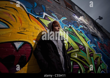 Trauriges Punk-Mädchen durch Graffitiwand stehen Stockfoto