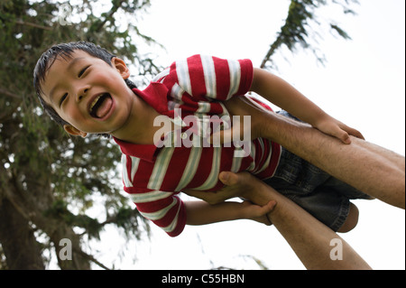 Asiatische junge lachend mit Mund offen, in der Luft geworfen, von Vater, USA Stockfoto