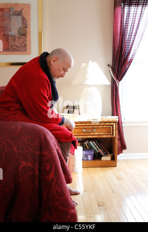 Reifer Mann sitzt auf Bett ernst Stockfoto