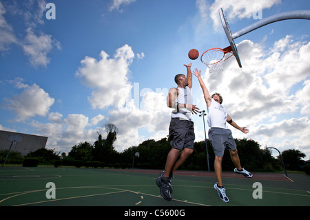 scoring bei Outdoor-Basketball-Spiel von zwei auf zwei männlich Stockfoto