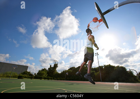 männliche machen Slam Dunk während der Outdoor-Basketball-Spiel, nach oben-Ansicht Stockfoto