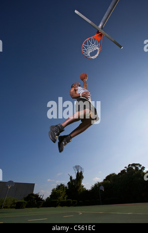 männliche macht Dunk, Layup auf Outdoor-Basketball-Ziel Stockfoto