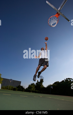 Männlich, scoring Layup auf Outdoor-Basketball-Ziel Stockfoto