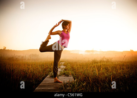 Mitte Erwachsene Frau tun morgen Yoga in einem Feld, obere Hering Lake Nature Preserve, Frankfort, Benzie County, Michigan, USA Stockfoto