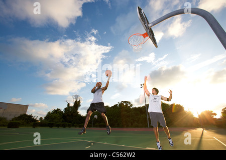 scoring während der Outdoor-Basketball-Gedränge zwischen zwei junge Männer männlich Stockfoto