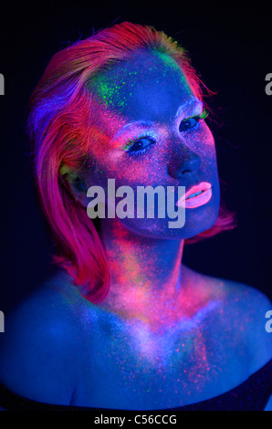 Weibliche Gesicht leuchtet in einem dunklen Raum mit fluoreszierenden Farben und Make-up unter Schwarzlicht Stockfoto