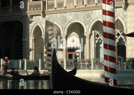 Ein Gondoliere führt Passagiere auf eine Gondelfahrt durch die Kanäle entlang der Fassade des Venetian Hotel in Las Vegas. Stockfoto