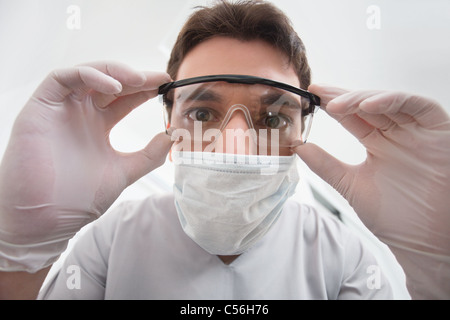 Nahaufnahme der junge Zahnarzt seine Brillen anpassen Stockfoto