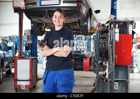 Porträt von lächelnden jungen weiblichen Mechaniker mit verschränkten in Autowerkstatt Stockfoto