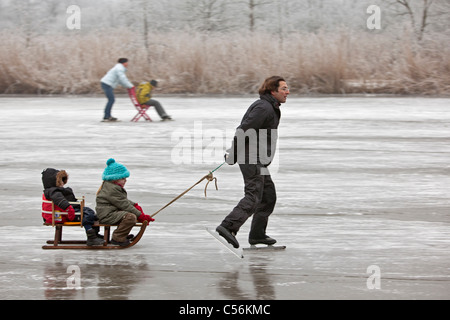 Den Niederlanden, Ankeveen. Mann und zwei Kinder auf Schlitten Eislaufen. Stockfoto