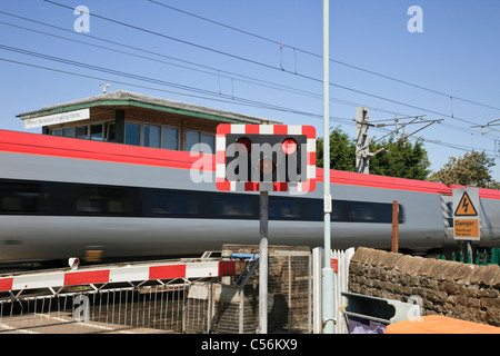 Main Line Bahnübergang mit roten leds mit hoher Geschwindigkeit Virgin Express Zug auf zu blinken. Hest Bank, Lancashire, England, Großbritannien, Großbritannien. Stockfoto