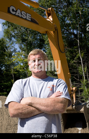 Bagger Fahrer steht stolz unter dem Arm seiner Maschine. Stockfoto