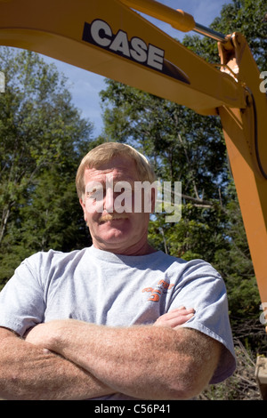 Bagger Fahrer steht stolz unter dem Arm seiner Maschine. Stockfoto