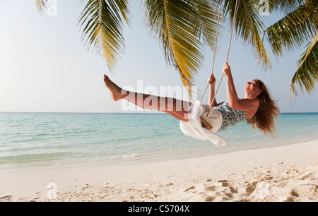 Lächelnde Frau schwingen am tropischen Strand Stockfoto