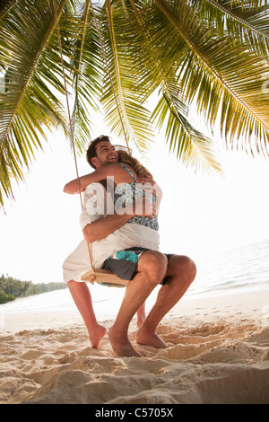 Paar auf Schaukel am Strand umarmt Stockfoto