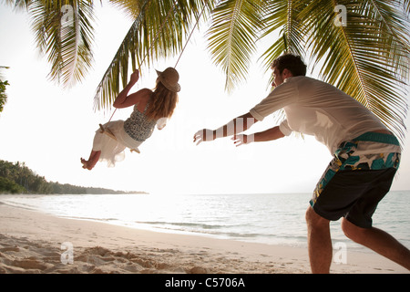 Mann schob schwingenden Frau am Strand Stockfoto