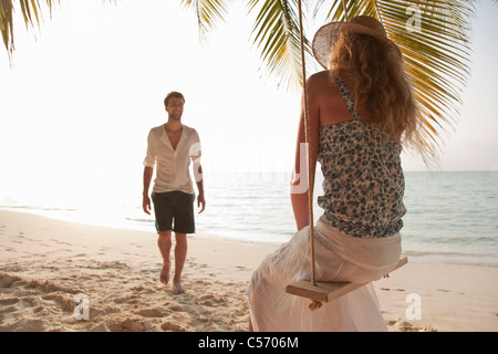 Frau auf Schaukel mit Freund am Strand Stockfoto