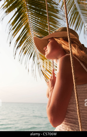 Frau sitzt auf Schaukel am Strand Stockfoto