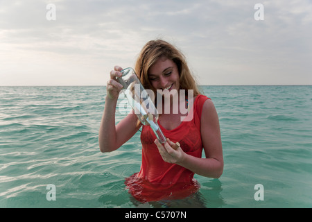 Frau im Meer mit Flaschenpost Stockfoto