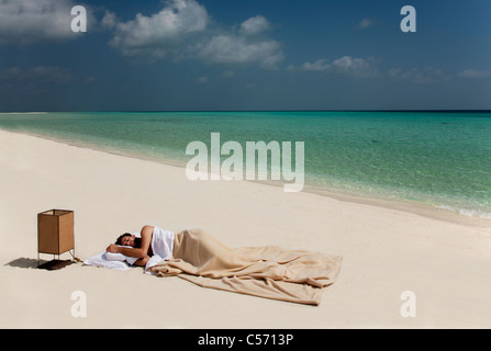 Mann im Bett am Strand schlafen Stockfoto