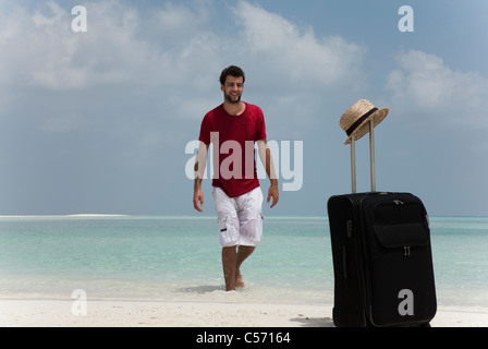 Mann mit Rollgepäck am Strand Stockfoto