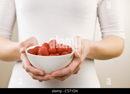 Frau Holding Schüssel mit Himbeeren Stockfoto