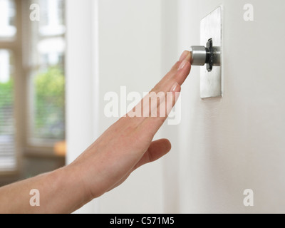 Frau Drücken des Knopfes an Wand Stockfoto