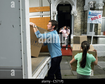 Familie Auspacken Boxen von Umzugswagen Stockfoto