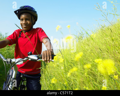 Junge Biken in Blumenfeld Stockfoto