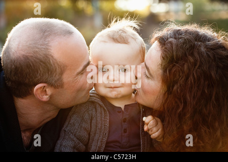 Eltern, die Babys im freien Wangen küssen Stockfoto