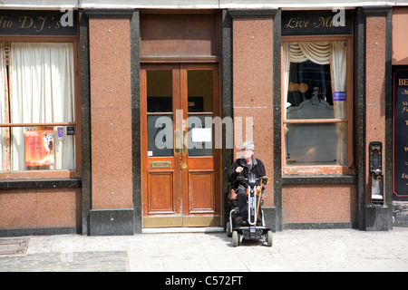 Älterer Mann auf Mobilität Roller vor pub Stockfoto