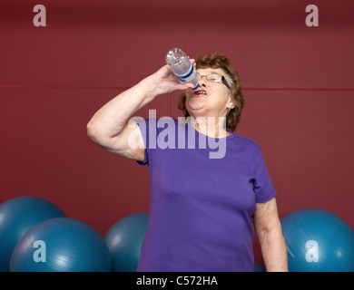 Ältere Frau Trinkwasser im Fitness-Studio Stockfoto