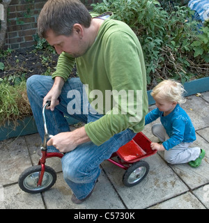 Pushing Vater des jungen auf Dreirad Stockfoto