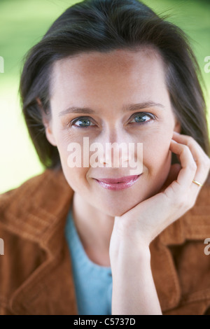 Lächelnde Frau ruht Kinn in die hand Stockfoto
