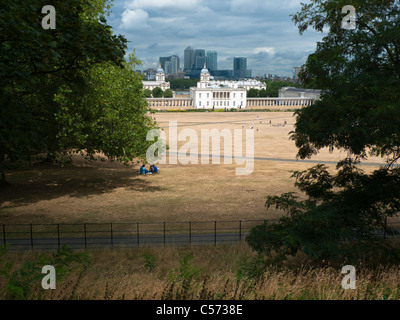 Blick über sehr trockene Greenwich Park in Richtung das National Maritime Museum in Greenwich, London, mit Docklands im Hintergrund Stockfoto