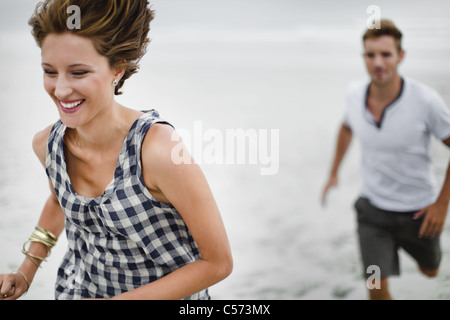 Paar jagten einander am Strand Stockfoto