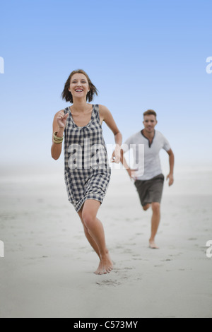 Paar jagten einander am Strand Stockfoto