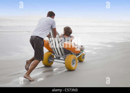 Mann schob Freundin in Karren am Strand Stockfoto