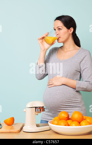 Foto von einer 32 Woche schwanger Frau in ihrer Küche trinken frisch gepressten Orangensaft. Stockfoto