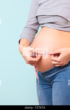 Foto von einer 32 Woche Preganant Frau ihren Bauch mit einem Maßband messen. Stockfoto