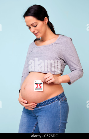 Foto von einer 32 Woche schwanger Frau hält das Datum ihr Baby soll sich gegen ihren Bauch, Ihr eigenes Datum ggf. hinzufügen. Stockfoto