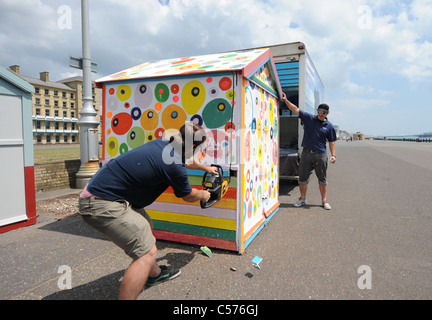 Jeff Allen beobachtet, wie seine psychedelischen Strandhütte in Hove UK entfernt und reduzieren durch die Kettensäge, nachdem der Rat Einwände gegen Farben Stockfoto