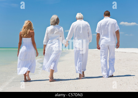 Rückansicht von vier Personen, zwei Senioren, Paare oder Familie Generationen Hand in Hand, an einem tropischen Strand zu Fuß Stockfoto