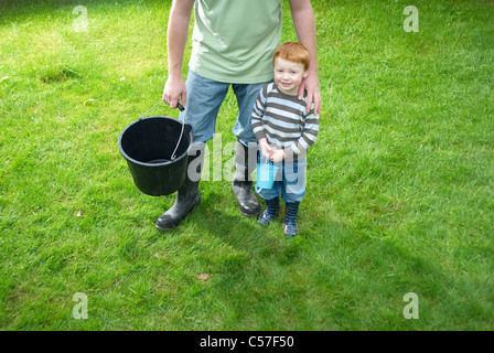 Vater und Sohn mit Eimern in Hinterhof Stockfoto